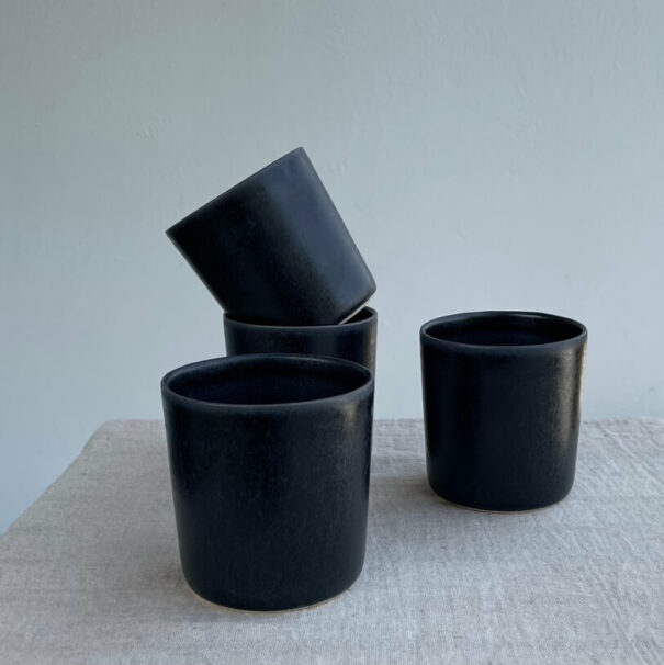 Multiple black ceramic mugs on table